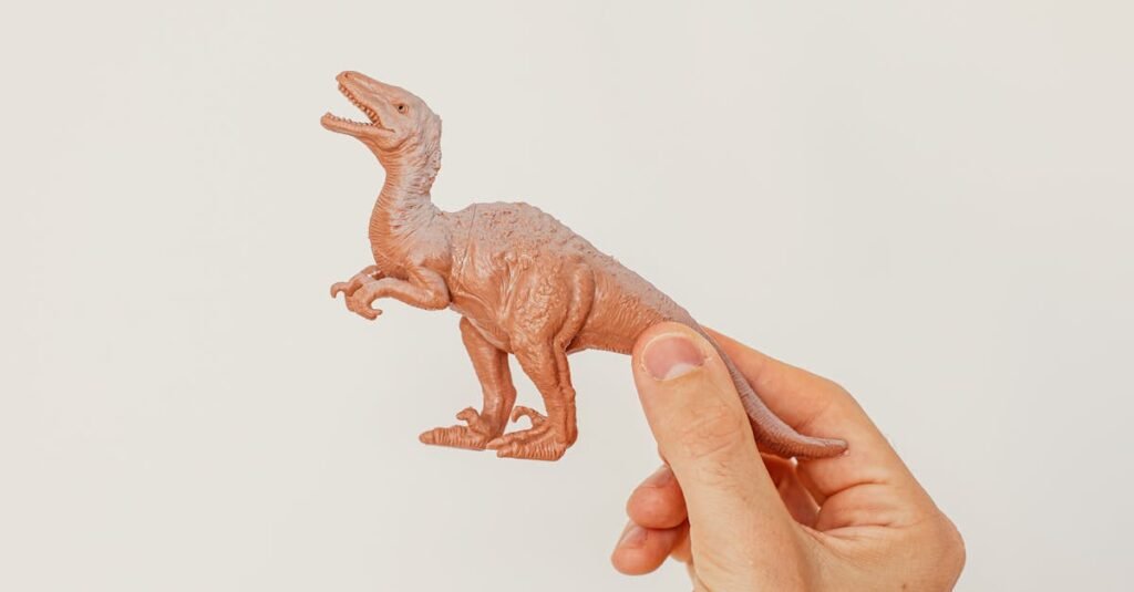 A hand holding a brown plastic dinosaur toy against a plain white background. Perfect for educational and creative uses.