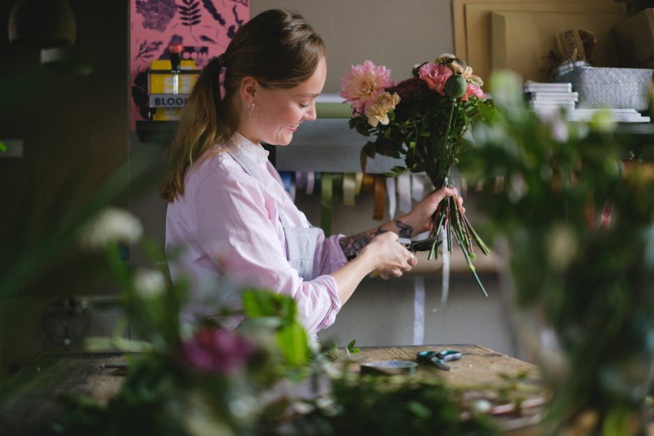 A woman florist arranging a colorful bouquet with precision in a stylish indoor studio.